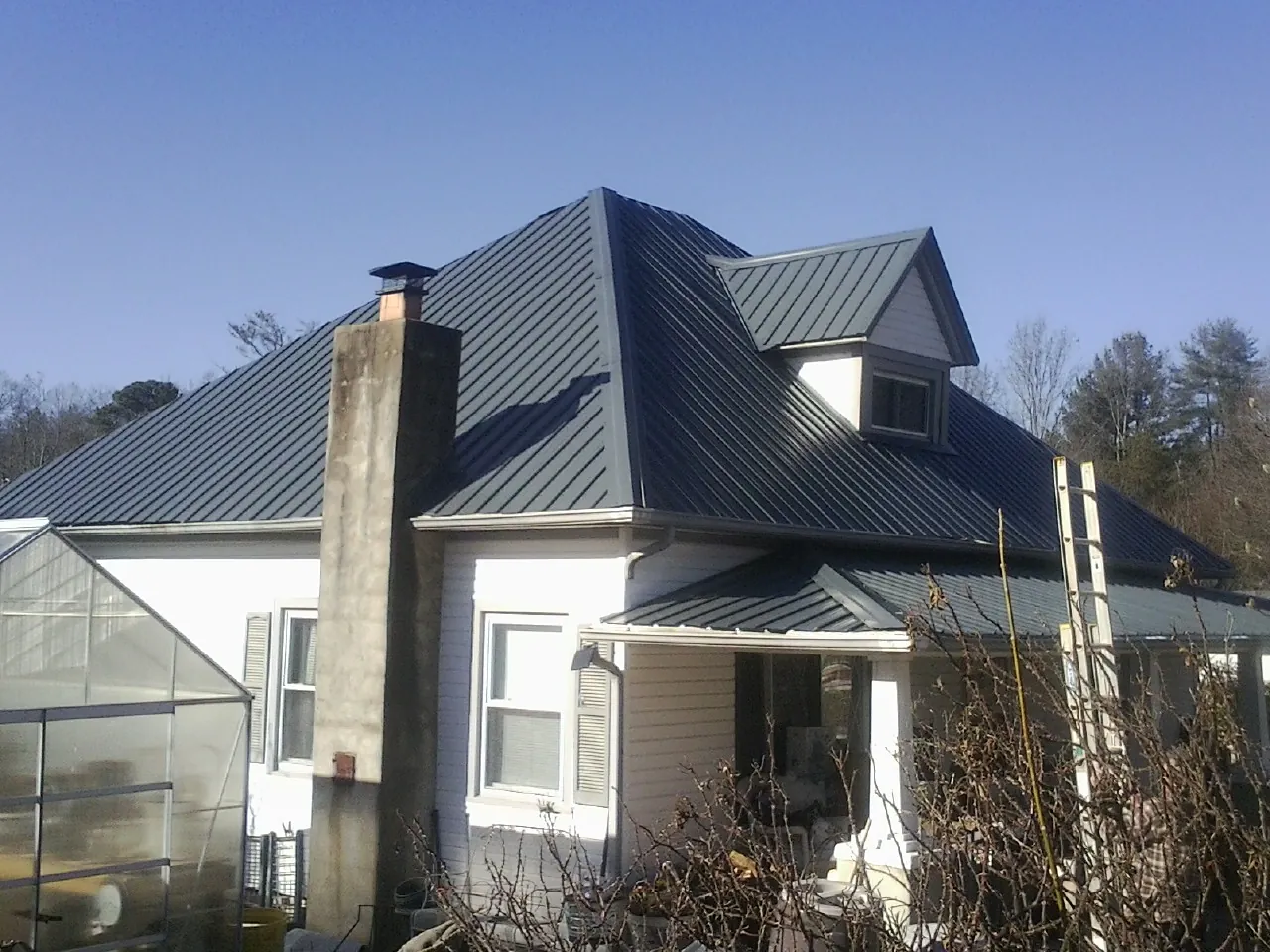 Dark blue standing seam metal roof on a white farmhouse with dormer — Slate & Tile Roof Repair by Roofing Brothers in Brattleboro