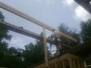 Carpenter setting a ridge beam over a new addition frame — Ice Dam Removal by Roofing Brothers in Brattleboro