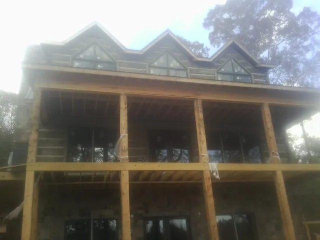 Dormers and porch framing on a large log home under construction — Roof Coating work by our crew in Brattleboro
