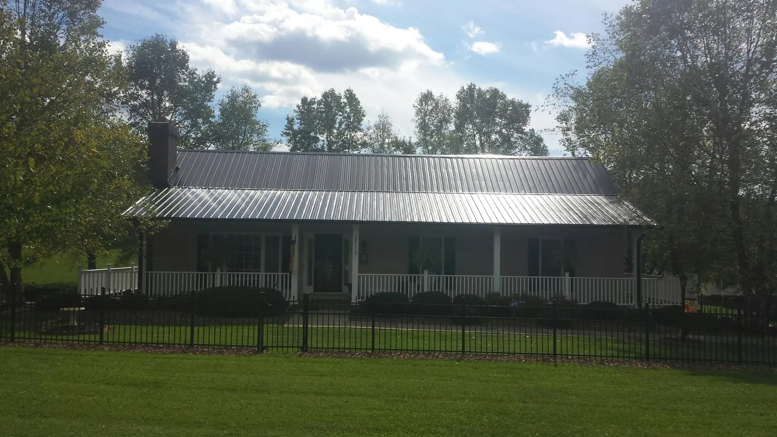 Gray metal roof on a brick ranch with a full width front porch — Gutter Guard Installation work by our crew in Brattleboro