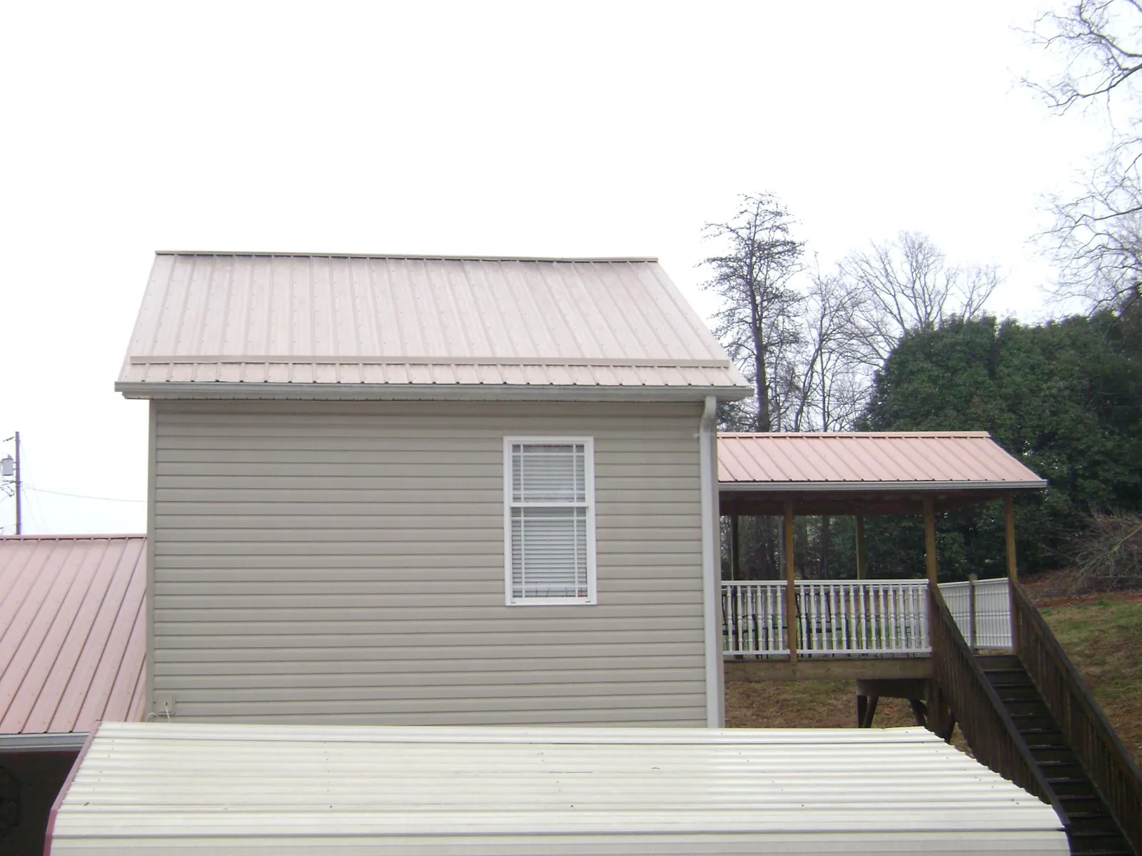 Tan metal roofs on a two story addition and attached porch, from a Roof Replacement job in Brattleboro