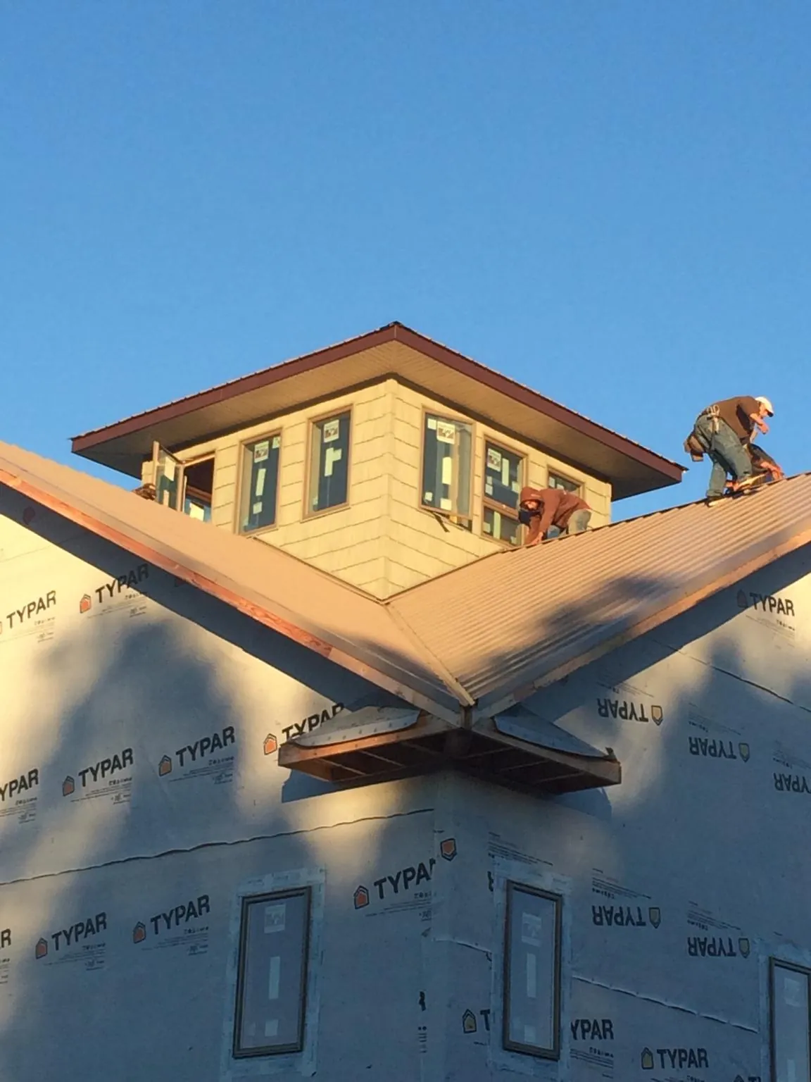 Roofers working around a rooftop cupola on a new metal roof at sunset — Roof Waterproofing in Brattleboro by Roofing Brothers